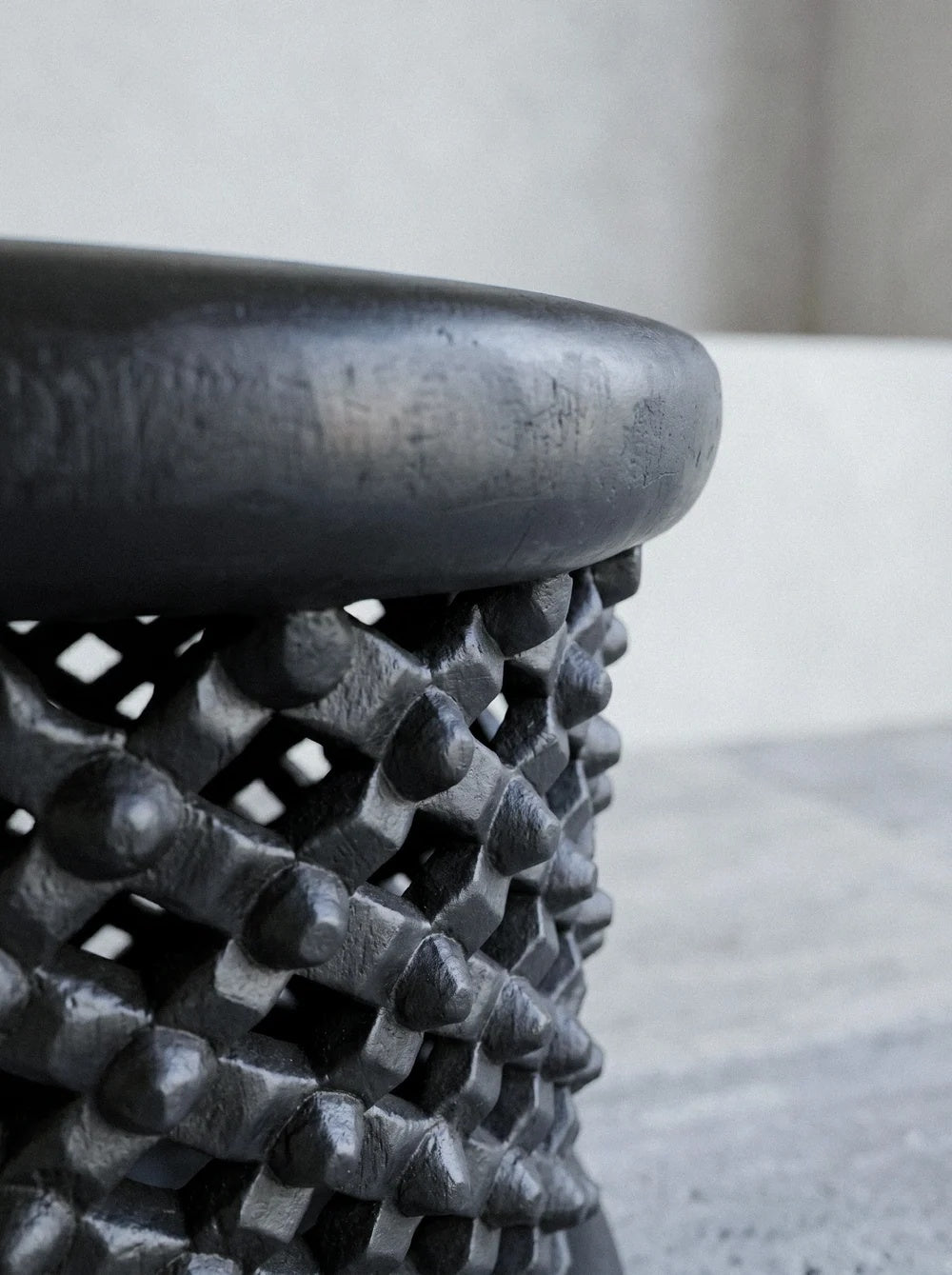 Détail des nœuds ciselés à la main et de la patine ébonisée mate du tabouret sculptural