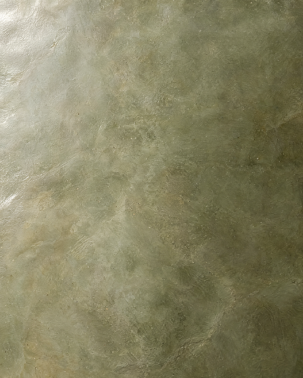 Close-up of polished sage tadelakt plaster with a stone-like sheen
